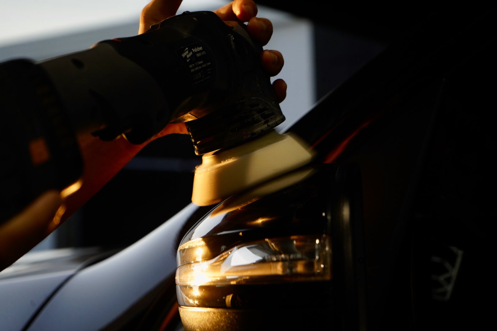 A machine polisher working a panel during paint correction