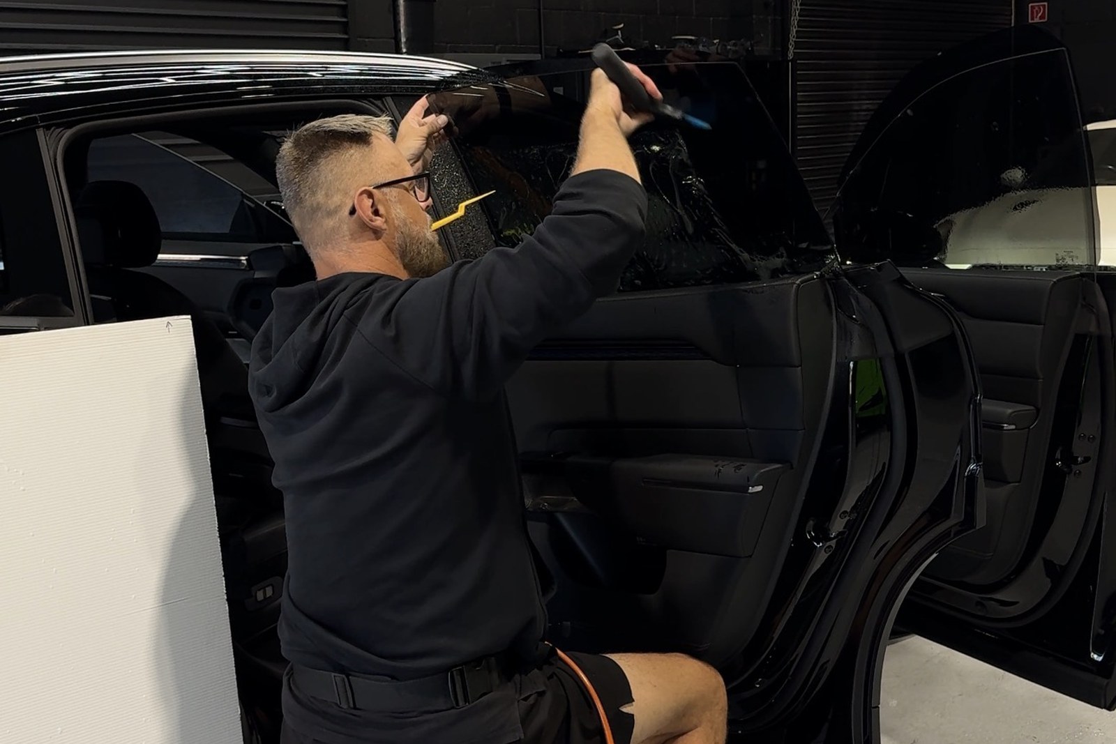 Ceramic window film being laid onto a rear door window in the workshop